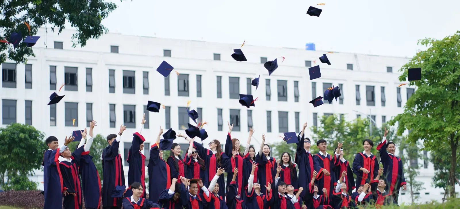 A graduation cap held up in front of a university building